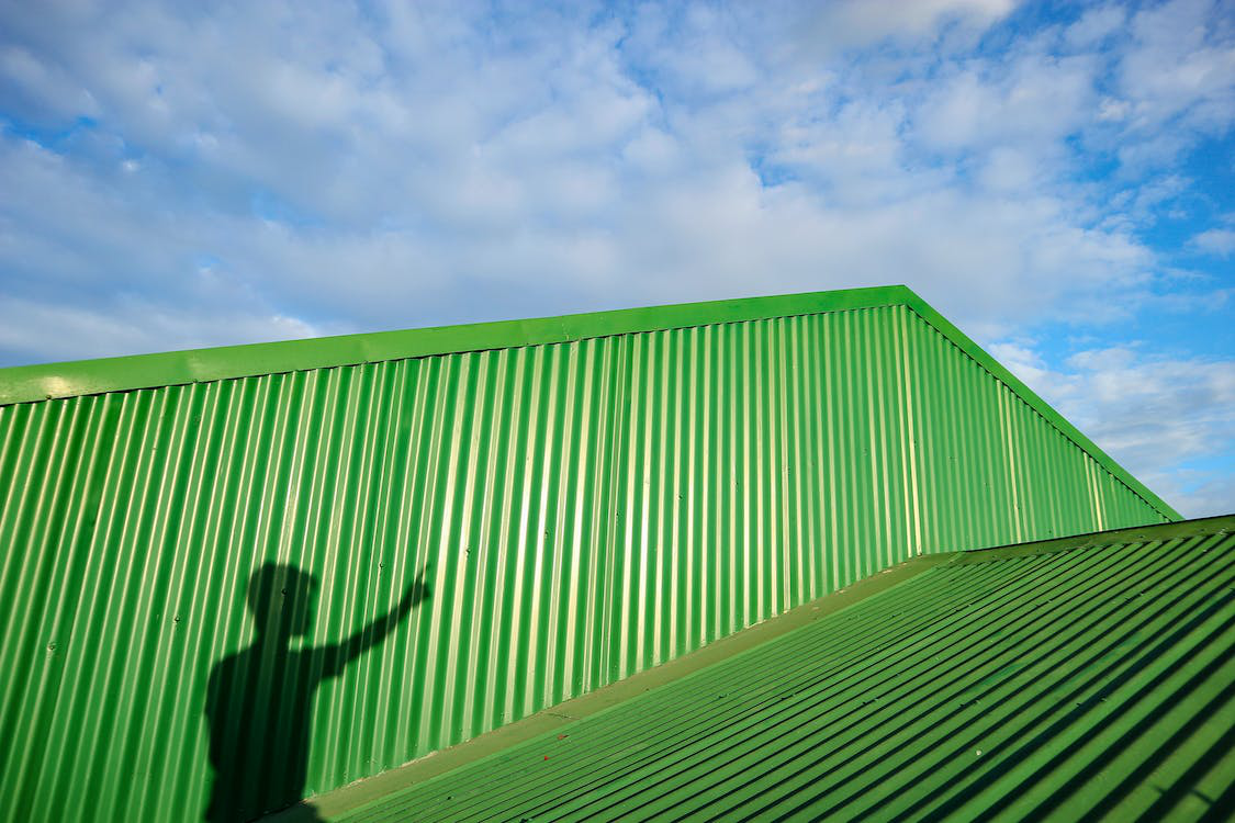 A Person's Shadow on a Green Metal Roof on a Clear, Sunny Day